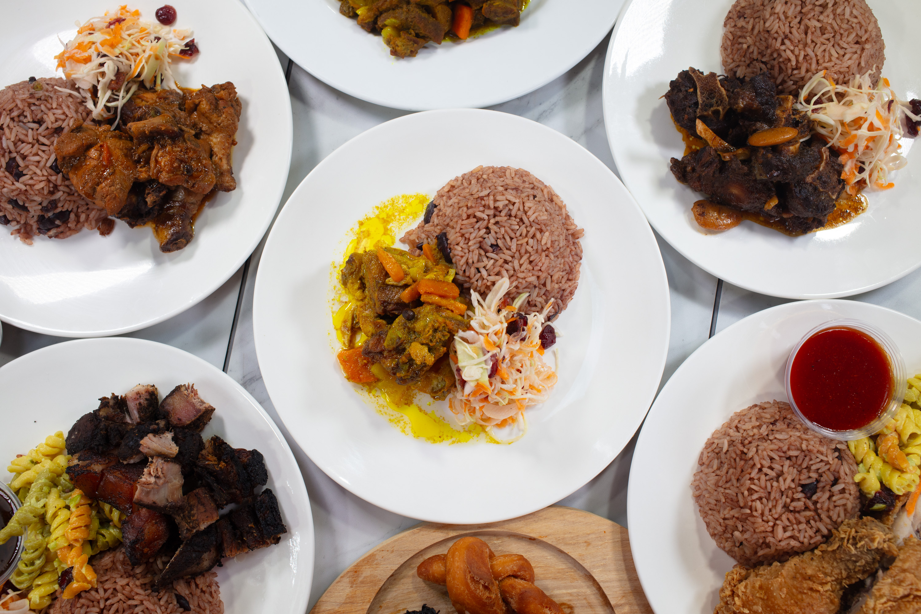 A spread of Hot Pot Caribbean Cuisine dishes with rice, vegetables, and island-style entrees